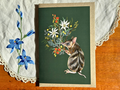Bandicoot greeting card with a native flower bouquet on dark green, on an embroidered doily on a wooden table