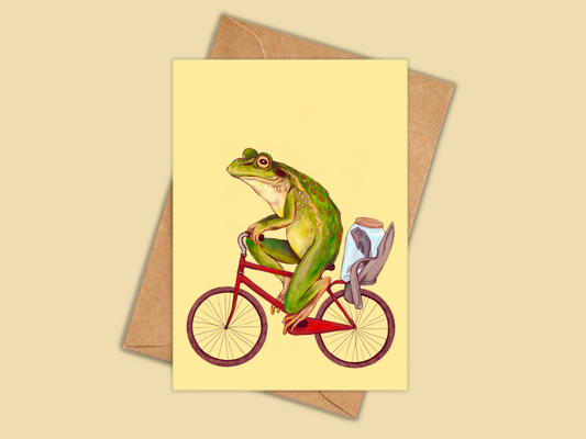 Bicycle Frog greeting card by Anna Seed: a frog riding a red bicycle with a fish in a jar on pale yellow