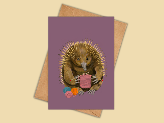 Echidna greeting card by Anna Seed: an echidna knitting a pink scarf beside balls of wool, on a plum purple background