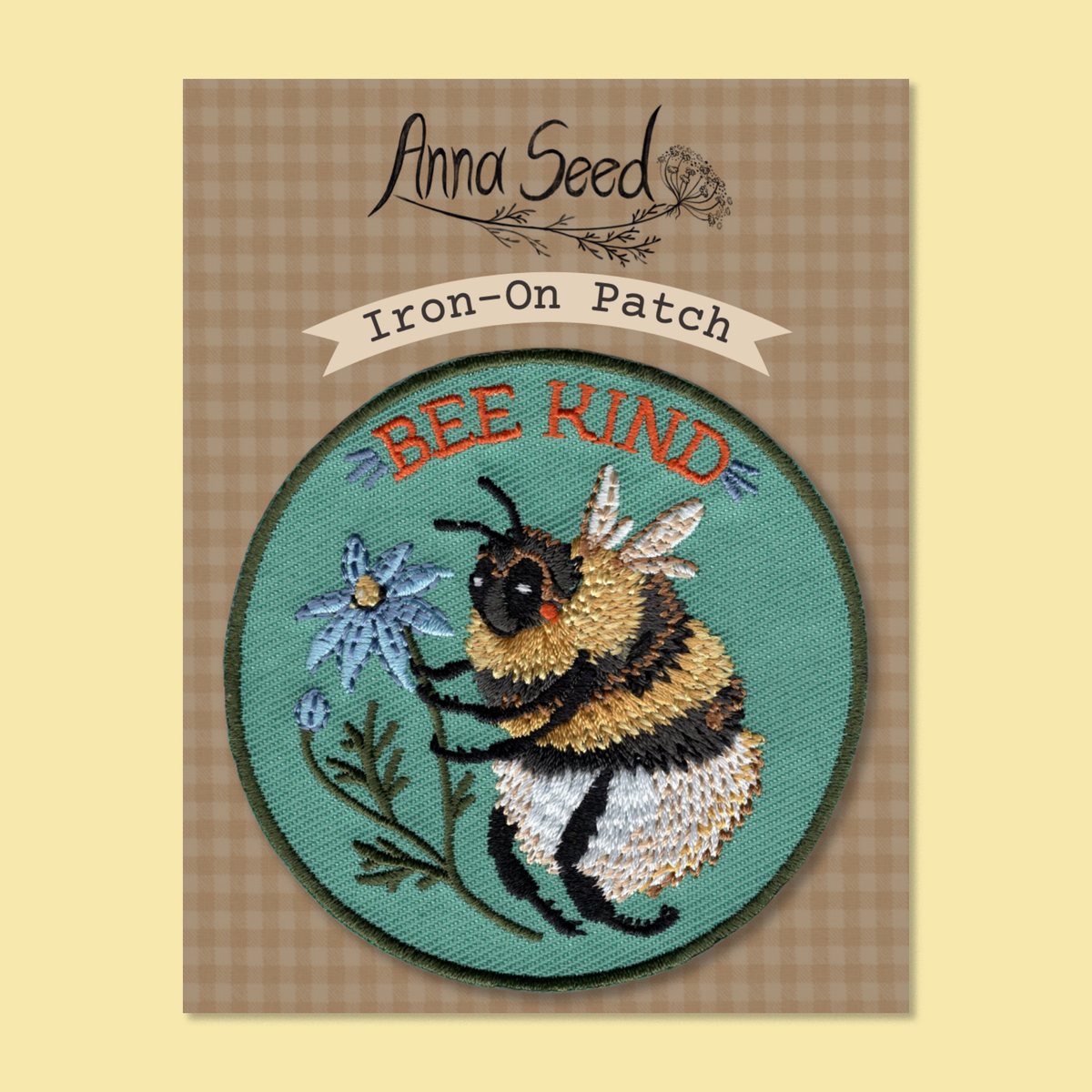 Bee Kind iron-on patch on its brown gingham backing card with an Anna Seed logo and Iron-On Patch label