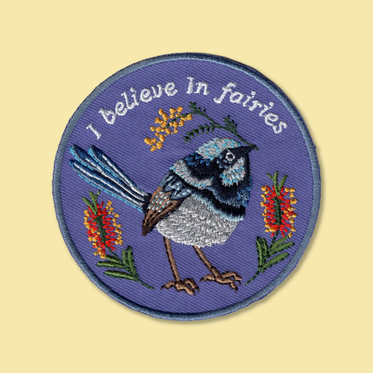 I Believe In Fairies iron-on patch by Anna Seed: an embroidered superb fairy wren among bottlebrush on lilac