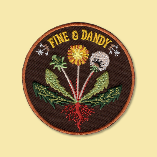 Fine & Dandy iron-on patch by Anna Seed: embroidered dandelion flowers, seed head, leaves and red roots on brown