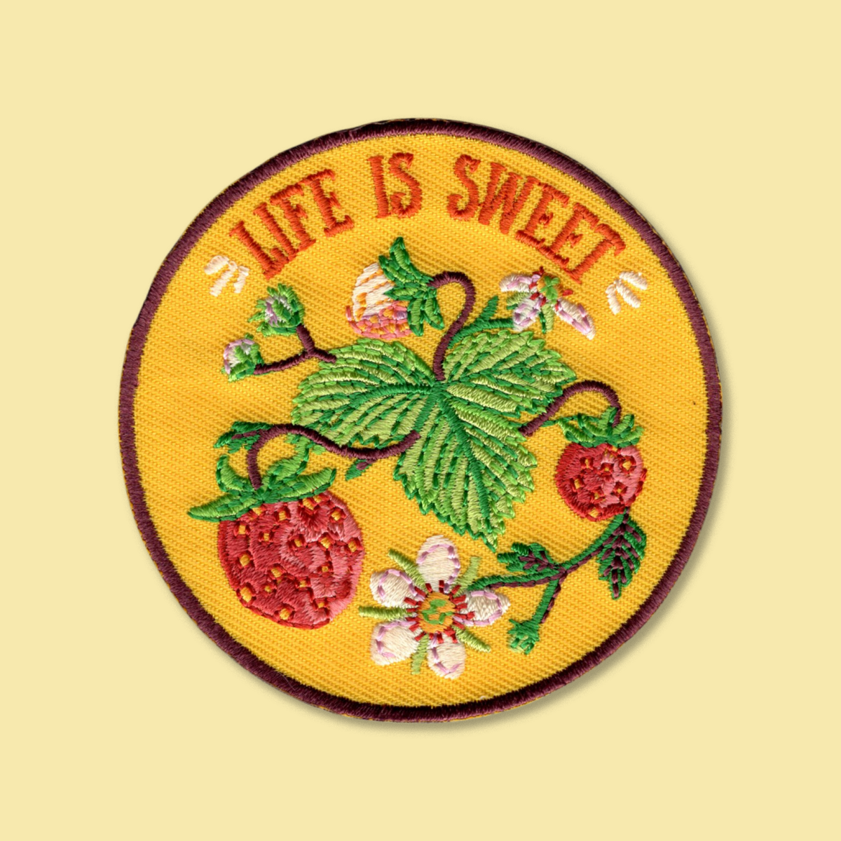 Life Is Sweet iron-on patch by Anna Seed: an embroidered strawberry plant with berries and white flowers on yellow