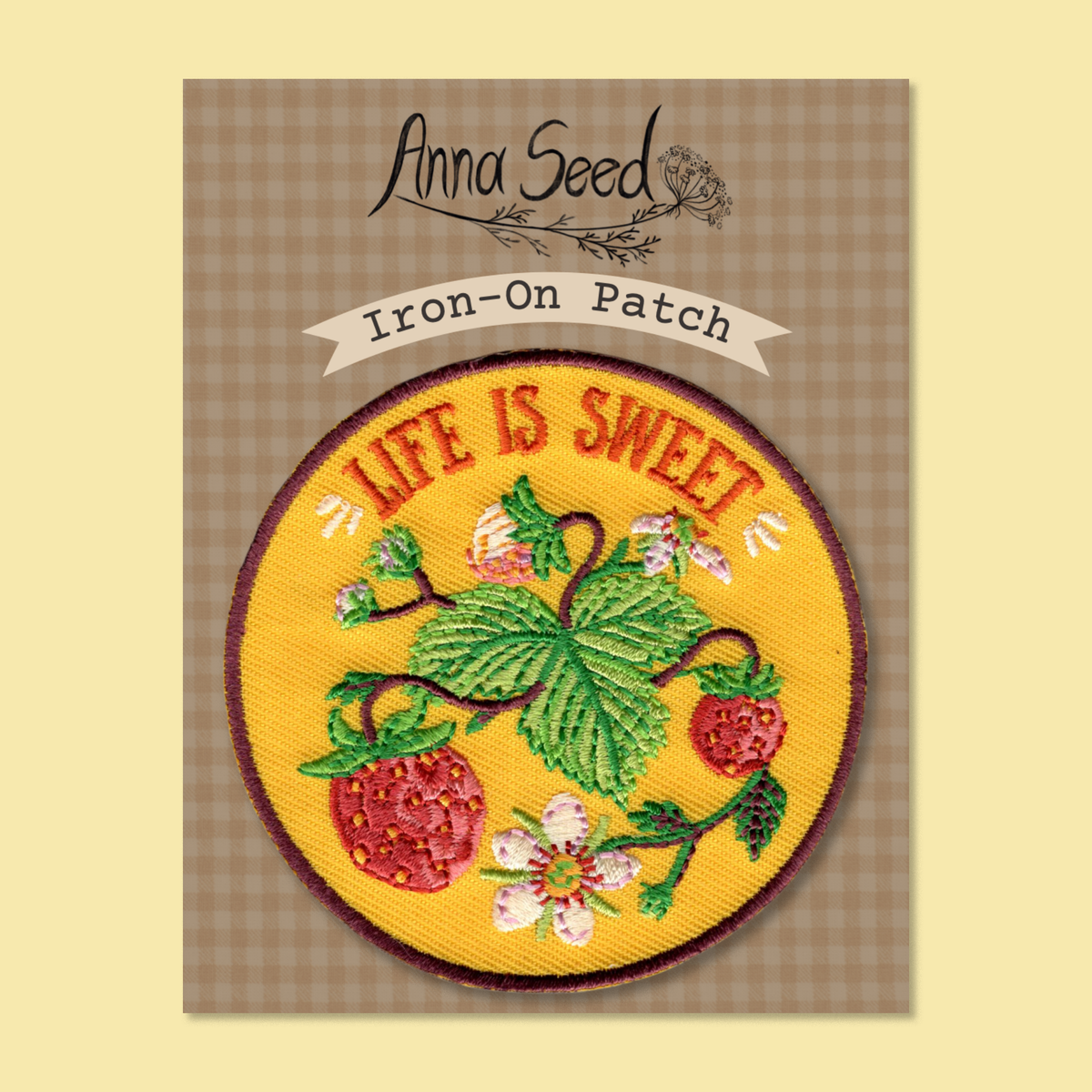 Life Is Sweet patch on its gingham Iron-On Patch backing card, red strawberries and leaves stitched on yellow