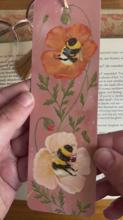 Video: Bumblebee Bibliophiles bookmark held in hand, showing two bees curled up reading inside poppy flowers