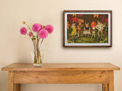 Autumn Jam landscape print of a woodland band, framed on a cream wall above a wooden table with pink dahlias