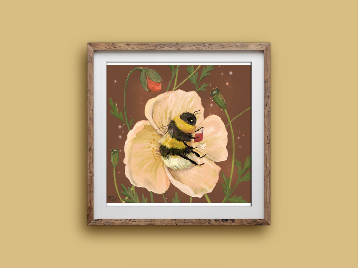 Bee Cosy art print in a wooden frame, a bumblebee curled up reading in a soft peach poppy, on a mustard wall