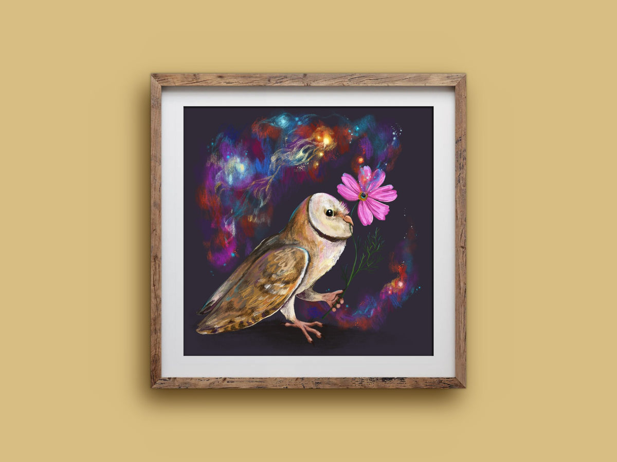 Cosmos print in a rustic square wooden frame on a mustard wall, showing a barn owl with a pink flower amid swirling nebulae