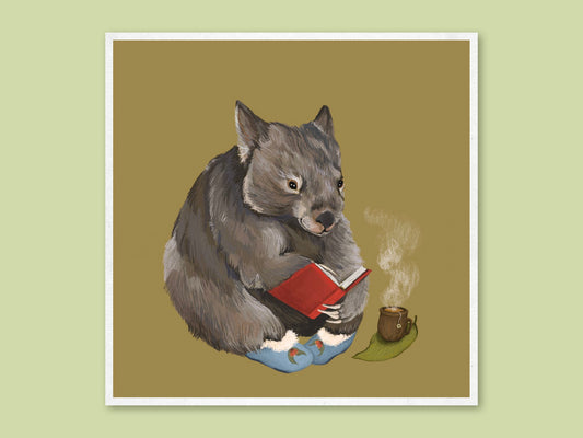 Cosy Wombat art print by Anna Seed: a wombat in blue slippers reads a red book beside a steaming cup of tea on olive green