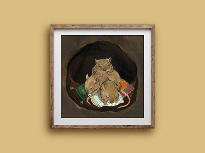 Cuddle Puddle print in a rustic square wooden frame on a mustard wall, showing three sleeping mice piled together in a burrow