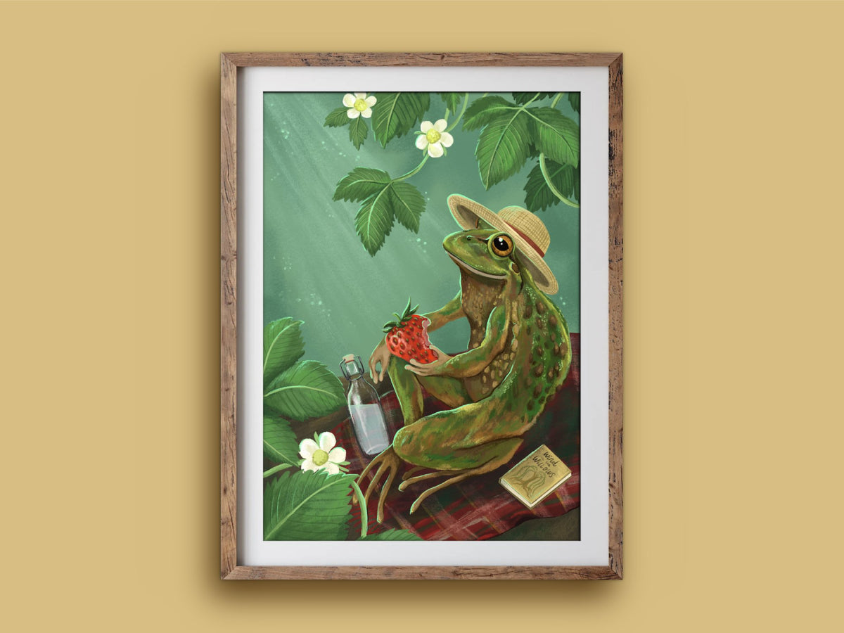 Froggie Picnic print in a rustic wooden frame on a mustard wall, showing a sunhatted frog picnicking with a book and a bottle