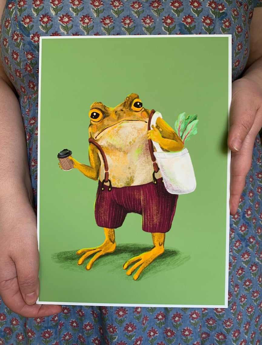 Hipster Toad print held in two hands against a floral dress, showing the coffee-carrying toad in braces on green