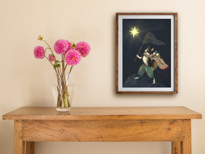 Framed On To The Next Life print hung above a wooden table with pink dahlias, a tuxedo cat reaching for a glowing star