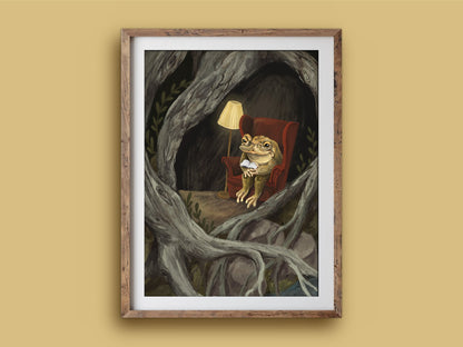 Reading Toad print in a wooden frame on a mustard wall, a cosy toad with a book and lamp inside a hollow of tree roots