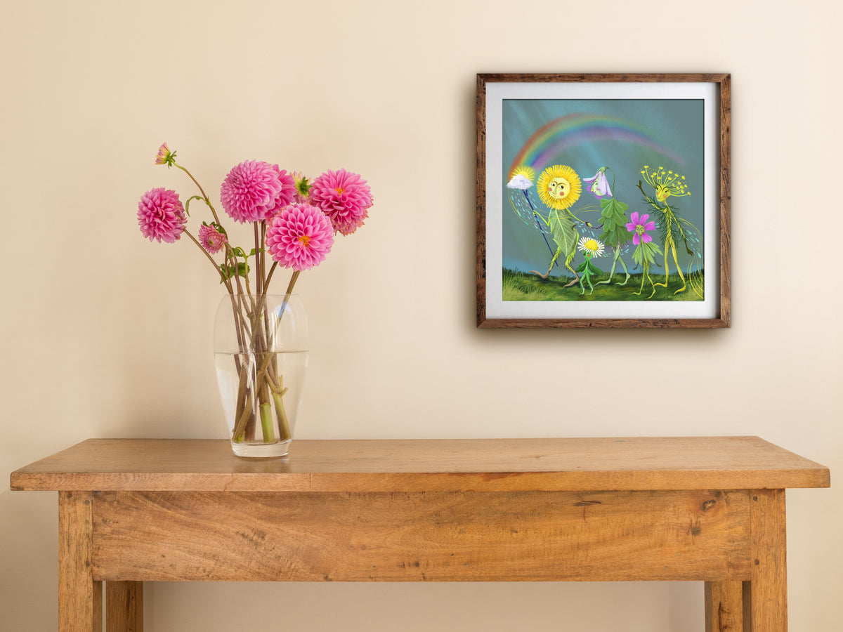 Framed Spring Parade square print hung above a wooden table with pink dahlias, showing the rainbow flower parade