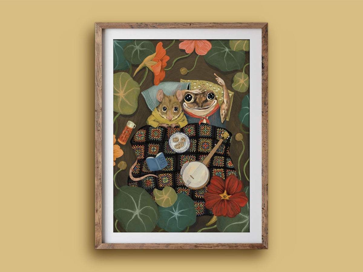 Starry Eyes print in a wooden frame on a mustard wall, mouse and frog campers with a banjo, book and biscuits