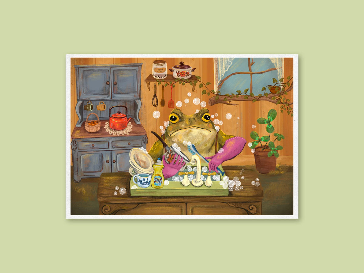 Toady Dishes landscape art print by Anna Seed: a grumpy toad in pink gloves scrubs bubbly dishes in a cosy kitchen