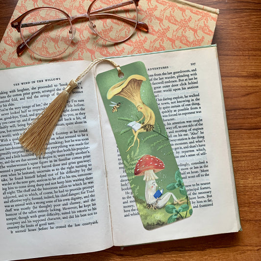 Mushroom Bookclub bookmark by Anna Seed on an open book by glasses, a chanterelle and a red toadstool both reading