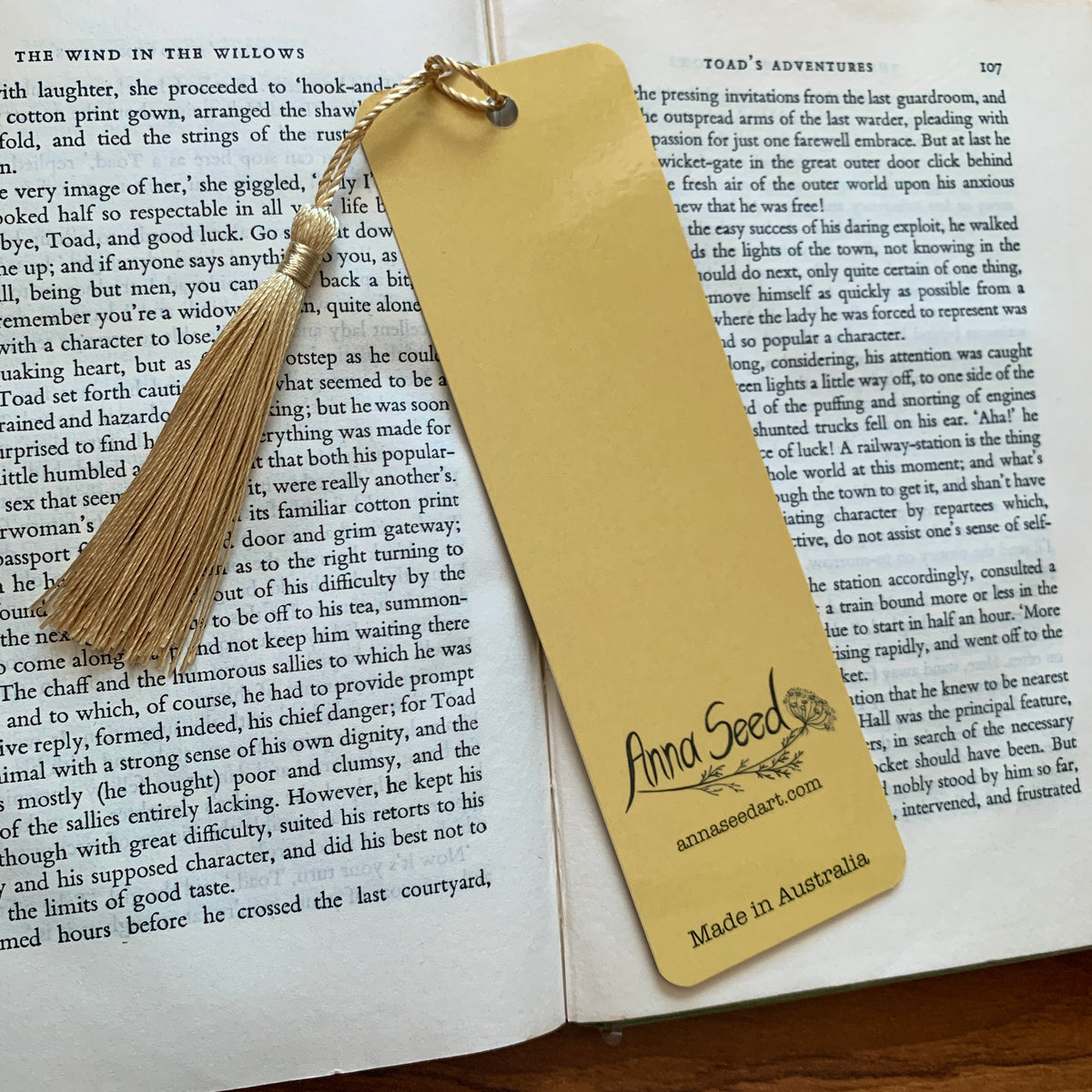 Mustard back of the Mushroom Bookclub bookmark with logo, website and Made in Australia text, on an open book