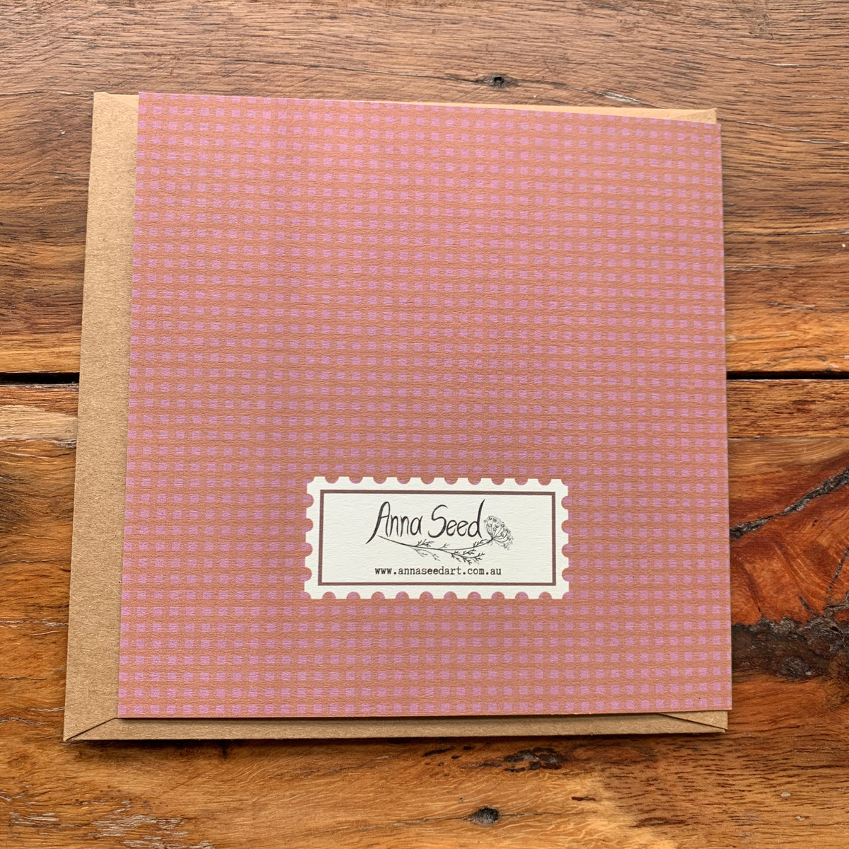 Back of the Happy birthday, I guess card in pink gingham with a stamp-style logo, on a kraft envelope